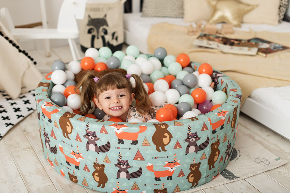 Little girl in a colorful ball pit with balls.