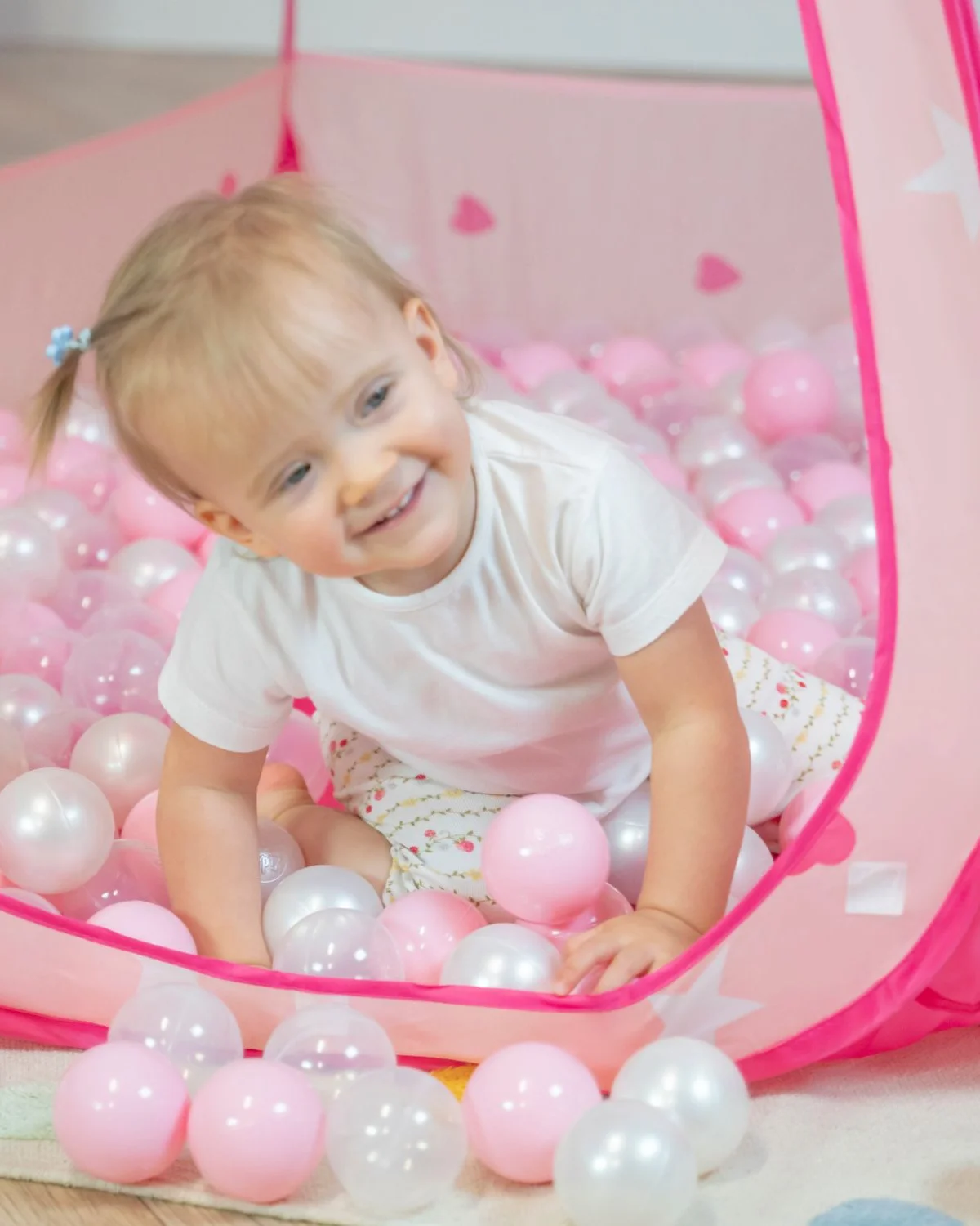 Child in a pink play tent with balls