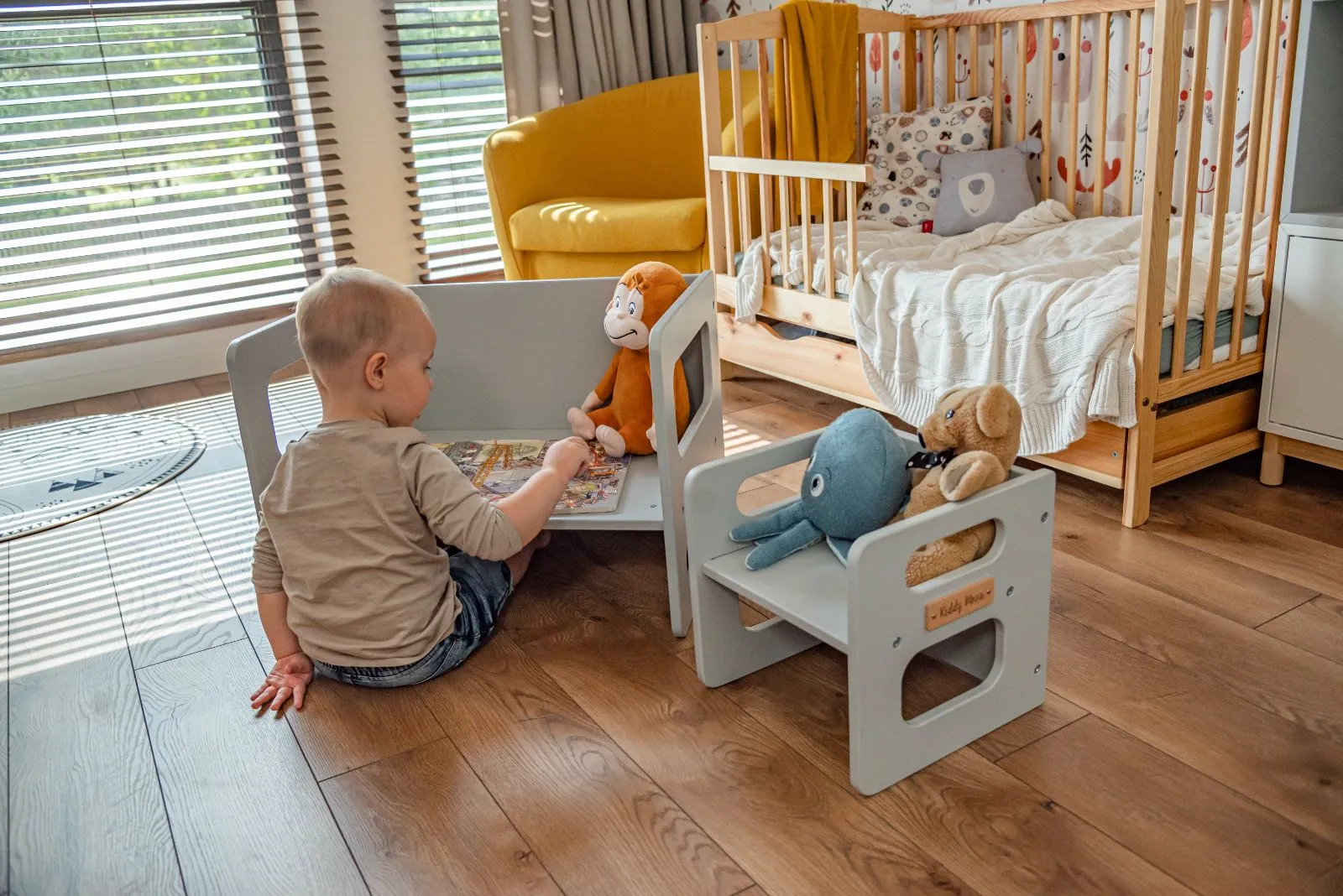 Toddler reading a book on the grey KiddyMoon storage bench