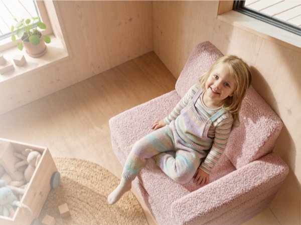 Child sitting in pink zippered fabric pod or cocoon-style seat